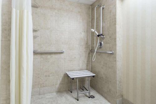 哥伦布Days Inn by Wyndham Columbus East Airport的浴室内配有带凳子的淋浴