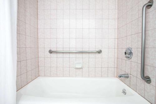 朗代尔南/曼哈顿海滩戴斯酒店的浴室内配有带白色浴缸的淋浴