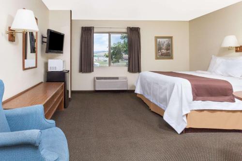 Wye米苏拉机场戴斯酒店的酒店客房,配有一张床和一张蓝色椅子