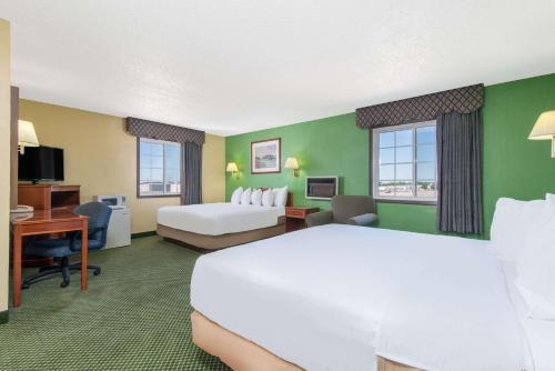 Great Bend戴斯大本德酒店的酒店客房设有一张白色大床和一张书桌