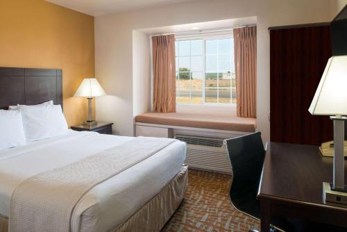艾尔韦高地艾尔威海兹/斯波坎机场戴斯旅馆及套房酒店的配有一张床、一张书桌和一扇窗户的酒店客房