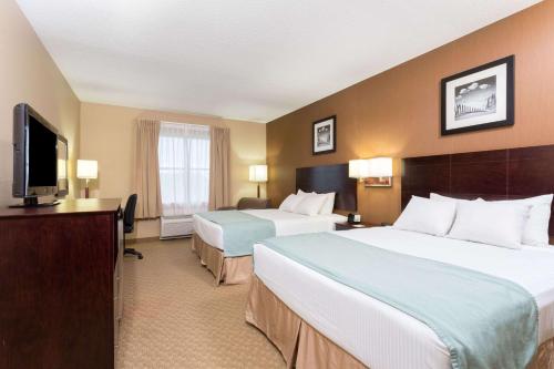 棕榈海岸Palm Coast Hotel & Suites-I-95的酒店客房设有两张床和一台平面电视。