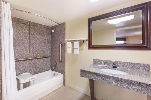 华纳罗宾斯Days Inn & Suites by Wyndham Warner Robins Near Robins AFB的一间带水槽、浴缸和镜子的浴室