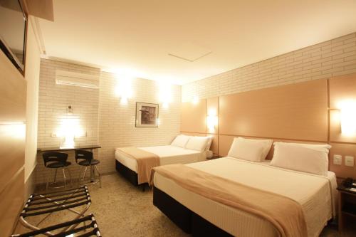 库里提巴Hotel Confiance Centro Cívico的酒店客房,设有两张床和两张桌子