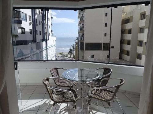 巴拉奈里奥-坎布里乌Jardim Europa的阳台上配有玻璃桌子和椅子,享有海景