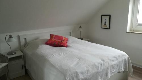 黑尔戈兰岛Haus Nautilus的一张白色的床,上面有红色枕头