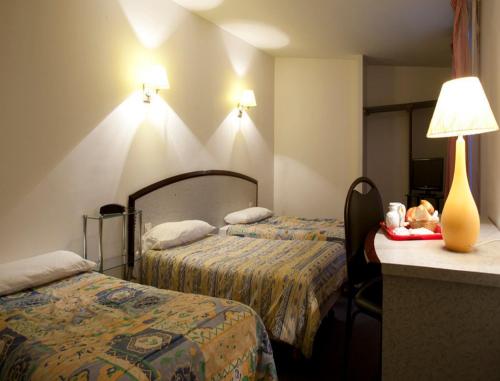 巴黎欧罗巴酒店的酒店客房设有两张床和一张带台灯的桌子。