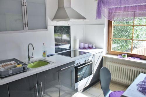 珀丽Ferienwohnung Guth的厨房配有白色橱柜、水槽和窗户。