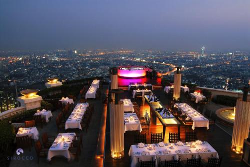 曼谷lebua at State Tower的大楼顶部设有白色桌子的餐厅