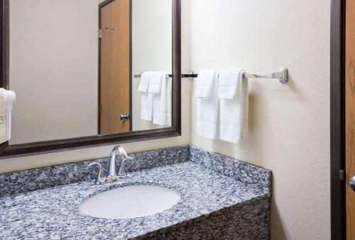 SartellAmericInn by Wyndham Sartell的浴室配有盥洗盆、镜子和毛巾