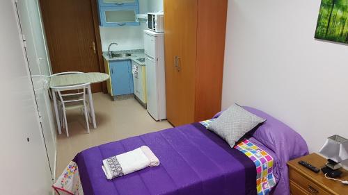 卡尔达斯·德·雷斯Apartamento Study 1 Select Real Caldas de Reis的带厨房的小客房内的紫色床