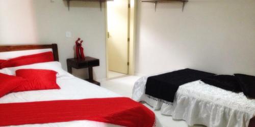 皮拉尼亚斯Milleniu's Pousada e Restaurante的一间卧室配有两张红色和白色床单