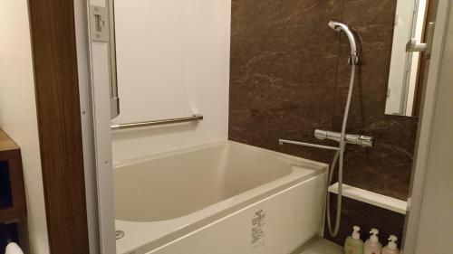 松茂町台黑悠酒店的带淋浴的浴室配有白色浴缸。