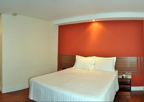 奥萨斯库Hotel Vollare的一间卧室配有一张白色的床和橙色的墙壁