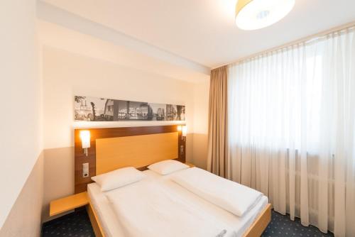 汉堡黑科托城市公园住宿酒店的一间卧室设有一张大床和一个窗户。
