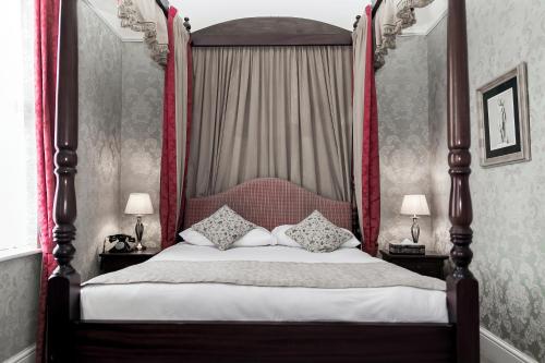 都柏林巴特勒联排别墅酒店的一间卧室配有一张带枕头的天蓬床。