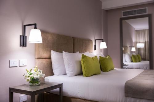 布宜诺斯艾利斯Howard Johnson Plaza Buenos Aires的卧室配有带绿色枕头的大型白色床