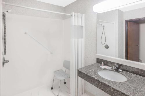 BrinkleyDays Inn & Suites by Wyndham Brinkley的一间带水槽、镜子和椅子的浴室