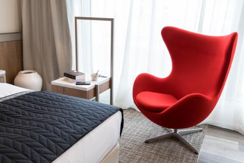 大阪心斋桥法拉格酒店 的一张红色椅子,坐在床边的卧室