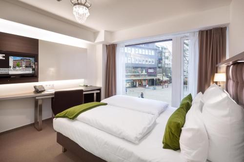 奥斯纳布吕克贝格曼奥斯纳布吕克寄宿旅馆的配有一张床、一张书桌和一扇窗户的酒店客房