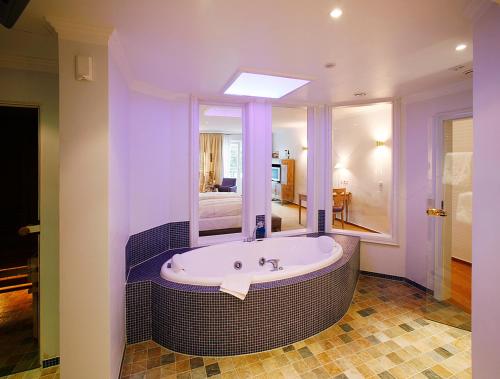 明斯特霍夫祖尔林德罗曼蒂克酒店的一间带大镜子和浴缸的浴室