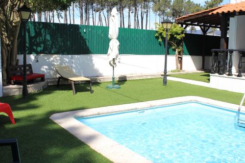 沙尔内卡Hostel Casa Lucas的庭院内的游泳池,配有遮阳伞和椅子