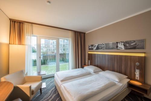 汉堡城市公园酒店的卧室配有床、椅子和窗户。