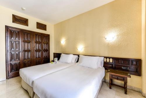 托莱多赛尔科特尔阿方索六世酒店的卧室设有一张白色大床和一扇窗户。