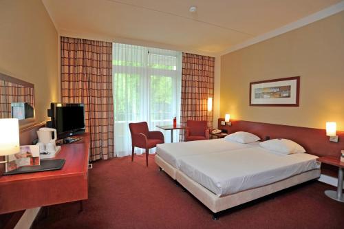 伯格达尔弗莱彻瓦尔蒙特公园酒店的酒店客房配有一张床、一张书桌和一台电视。