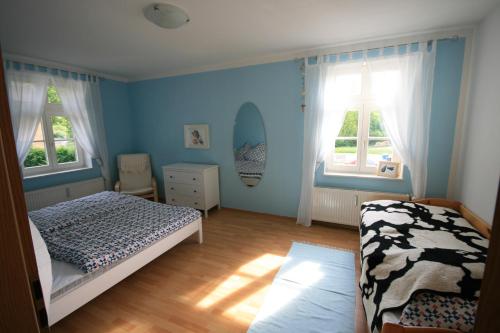 卢布明Ferienhaus Schwalbe Seebad Lubmin的一间拥有蓝色墙壁的卧室、一张床和两个窗户