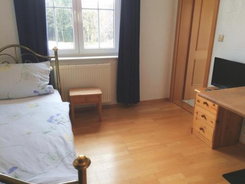 SchlierFuchsenlohe的一间卧室配有一张床、梳妆台和电视。