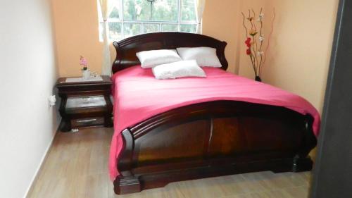 蒙圭Portal de la Cascada - Mongui的一间卧室配有一张带粉色毯子的木床