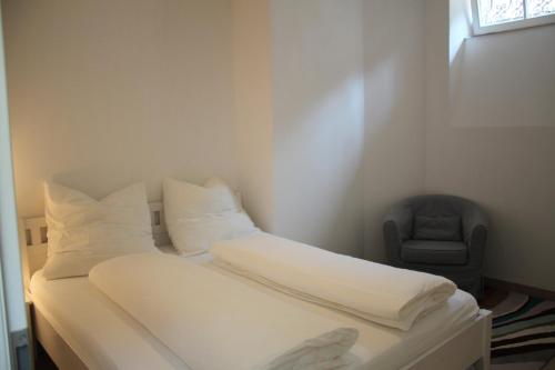 维尔茨堡Stadtvilla Würzburg的一间卧室配有一张带白色床单和椅子的床