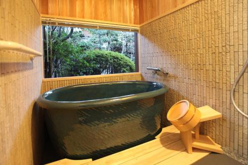 仓敷日奥日克昂特斯吉塔酒店的一间带大型绿色浴缸和窗户的浴室