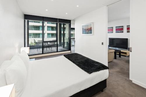 吉朗埃吉沃特207公寓的白色卧室设有一张大床和电视。
