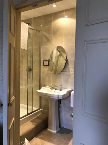 诺里奇Stower Grange Hotel的浴室配有盥洗盆和带镜子的淋浴