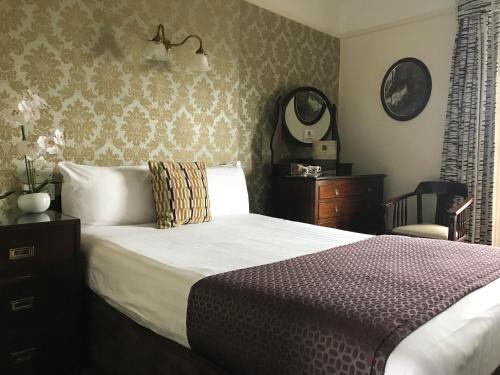 基尔肯尼基尔肯尼俱乐部酒店的一间卧室配有一张床、镜子和椅子