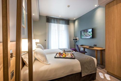 巴黎马格兰酒店的一间酒店客房,配有一张床铺,上面放着一个食物托盘