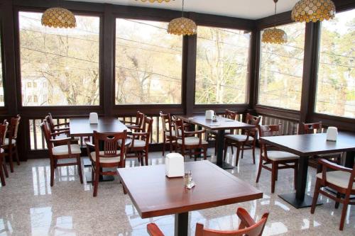 拉姆尼库沃尔恰米拉吉酒店的餐厅设有桌椅和大窗户。