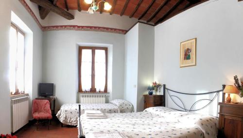 蒙特普尔恰诺斯塔兹奥Agriturismo Le Stringaie的一间卧室设有两张床、一台电视和两个窗户。