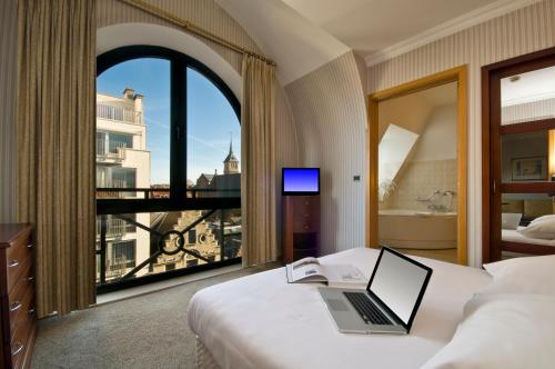 布鲁塞尔昂比奥里克斯B公寓式酒店的酒店客房设有一张带笔记本电脑的床和窗户。