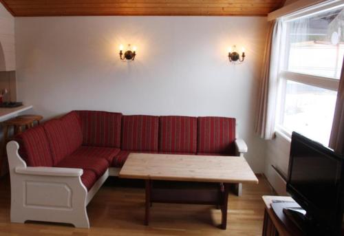Årøy依文特利吉斯咖雷特酒店的客厅配有红色的沙发和桌子