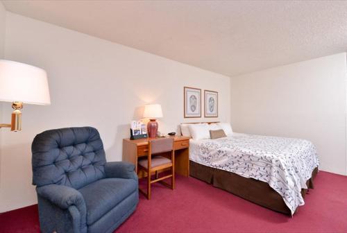 国际瀑布城America's Best Value Inn & Suites International Falls的一间卧室配有一张床、一把椅子和一张书桌