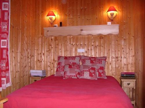 勒蒂约Nice chalet with dishwasher, in the High Vosges的一间卧室配有一张带红色床单的床和两盏灯。