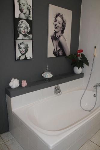 戈登湾Merci Pére的浴室设有白色浴缸,墙上挂有图片