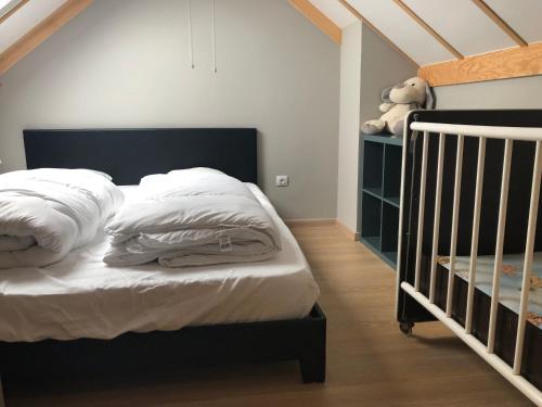 文代讷Beachhouse Wenduine 25的一间卧室配有一张带白色床单和一张婴儿床的床。