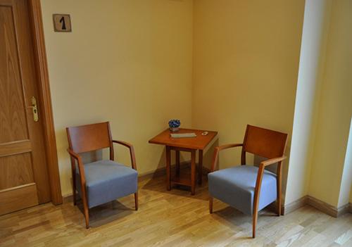 巴利亚多利德Hostal Puerta del Valle的一间设有两把椅子、一张桌子和一张桌子的房间