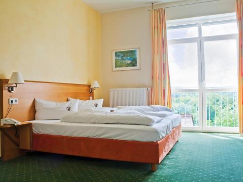 施奈塔赫伊格沃特伯格霍夫酒店的一间卧室设有一张床和一个大窗户