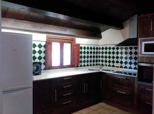 TronchónEl Rincón del Gallo的厨房配有木制橱柜和绿色及白色瓷砖