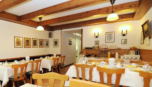 杜塞尔多夫乌特巴赫沃尔德酒店的餐厅设有白色的桌椅和木制天花板。